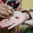 Hinduistische Frau, die das Swastika-Zeichen auf eine Hand malt