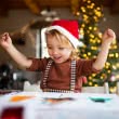 Kind malt mit Weihnachtsbaum im Hintergrund