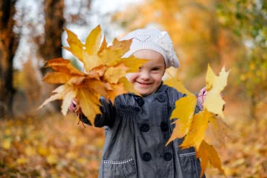Ein Mädchen mit bunten Herbstblättern in der Hand