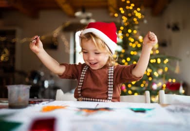Kind malt mit Weihnachtsbaum im Hintergrund